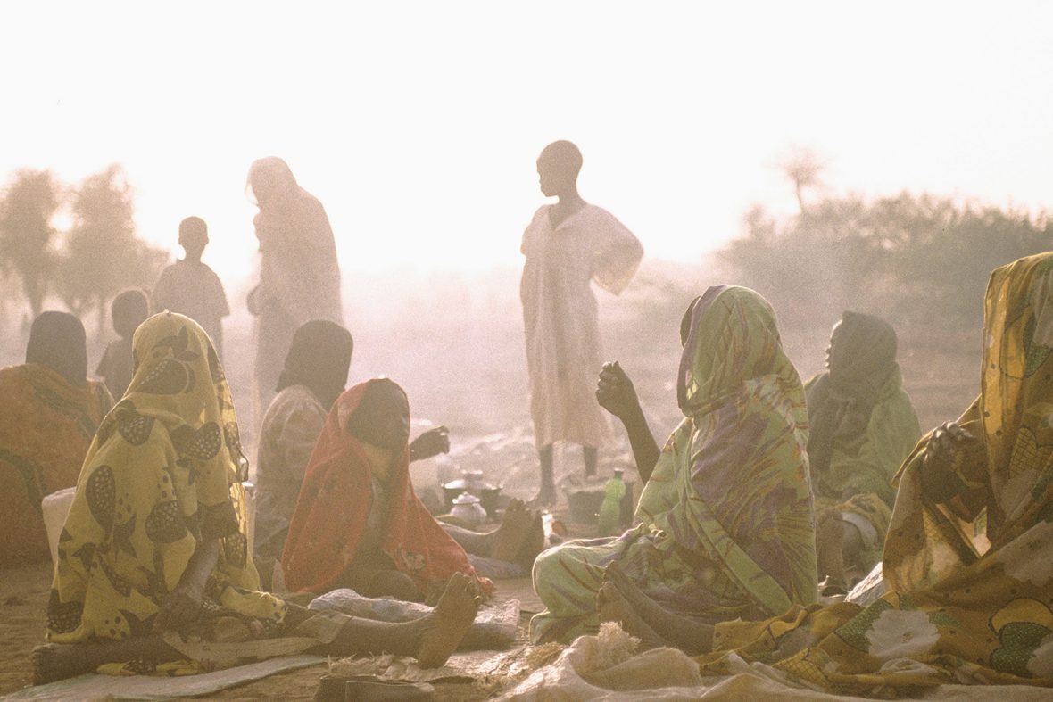 IDPs (internally displaced people) who have fled attacks on their villages by the Janjaweed militia drink early morning tea at Meshtel camp, where they have settled.  They have no shelters there: their homes are the mats they are sitting on.